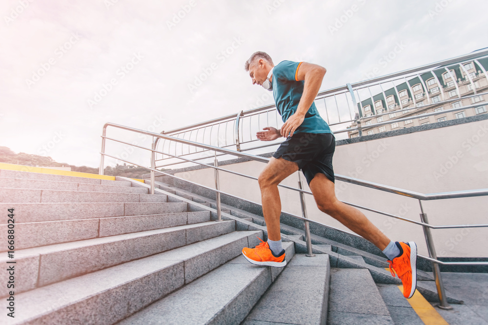 healthy lifestyle middle aged man runner running upstairs on city stairs. vintage color