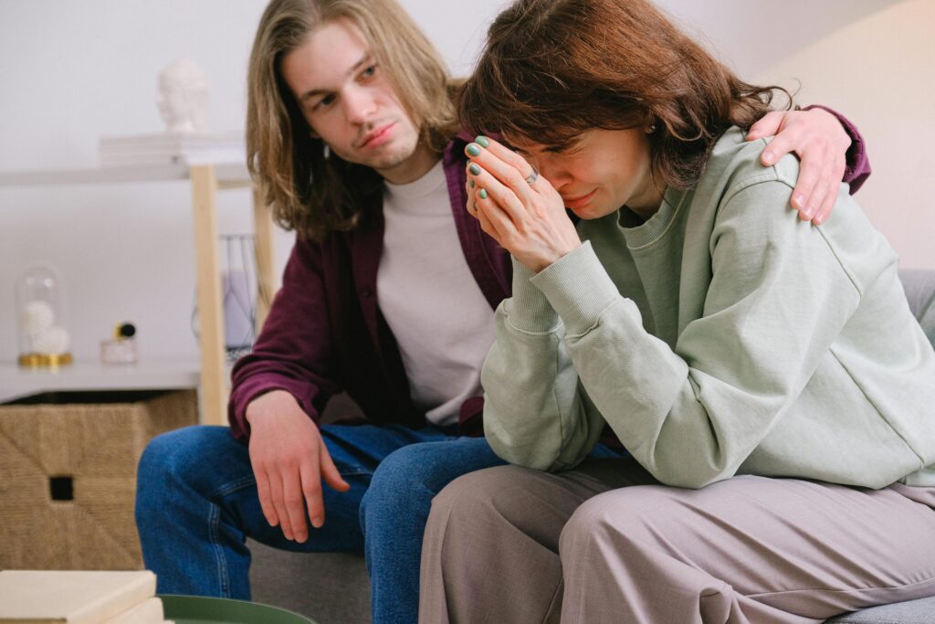 Man comforting crying sorrowful woman with hands together